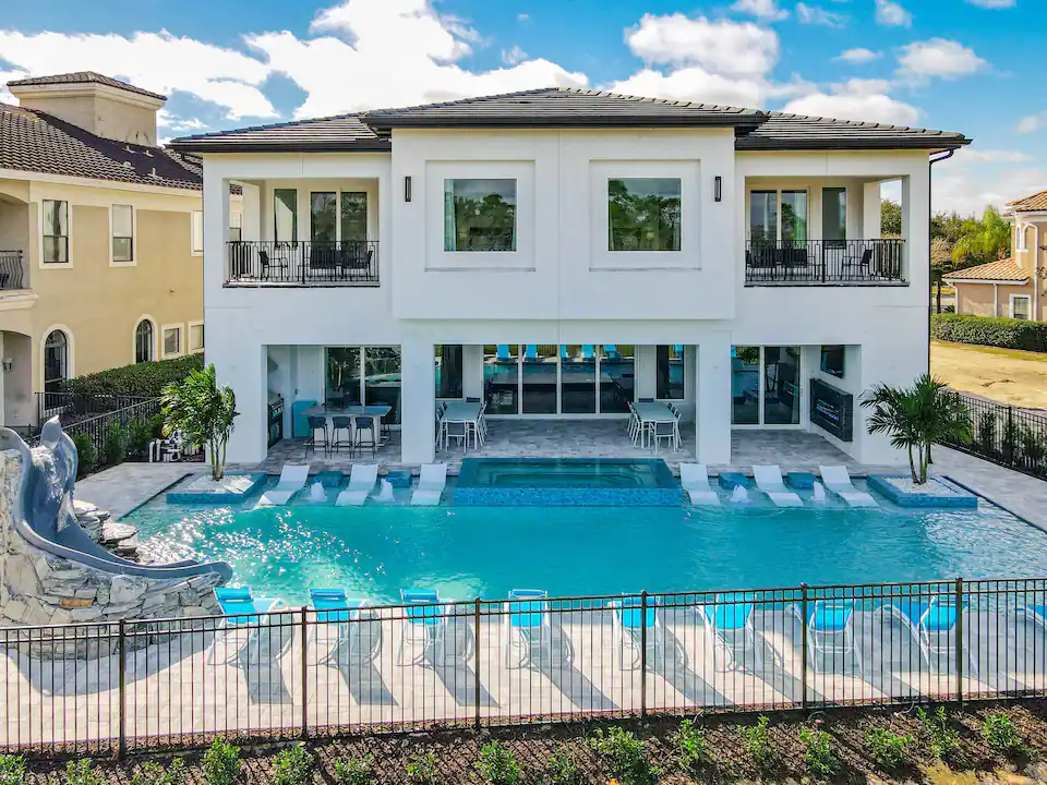 A resort-style pool with lounge seating and a water slide at an Orlando vacation home.